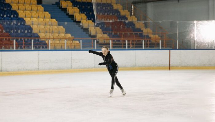 A young woman elegantly figure skating on an indoor ice rink, showcasing her skills. - Photo by Pavel Danilyuk on Pexels