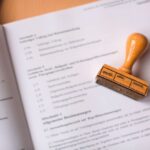 Close-up of a legal document with a wooden stamp placed on top, highlighting verification. - Photo by Markus Spiske on Pexels