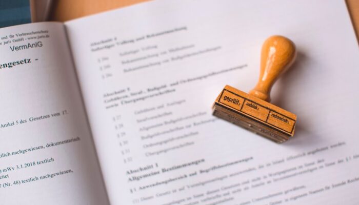 Close-up of a legal document with a wooden stamp placed on top, highlighting verification. - Photo by Markus Spiske on Pexels