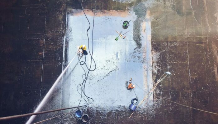 Top view of workers cleaning a large surface with equipment and water hoses. - Photo by Saruhan Osmanoğlu on Pexels