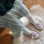 Top view of fuzzy slippers on a sheepskin rug, evoking warmth and comfort. - Photo by https://kaboompics.com/ on Pexels