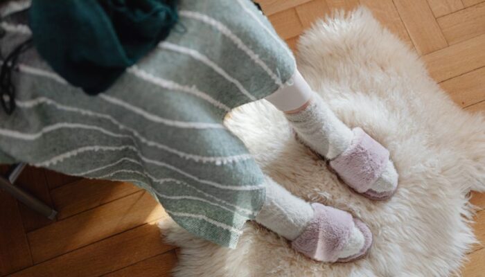 Top view of fuzzy slippers on a sheepskin rug, evoking warmth and comfort. - Photo by https://kaboompics.com/ on Pexels