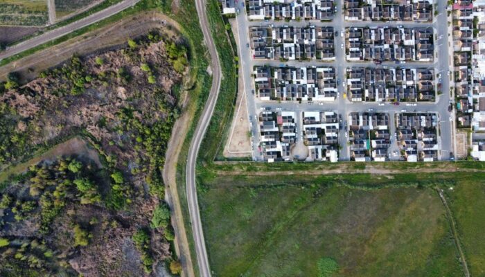 Drone view of a residential neighborhood alongside a natural landscape, showcasing urban and rural contrast. - Photo by Jorge Alvarado Gutierrez on Pexels